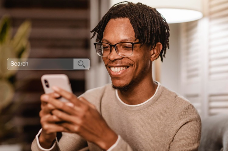 Homem sorrindo e digitando em um celular com uma barra de busca virtual aparecendo acima do aparelho